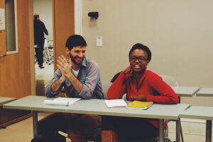 Two students enrolled in the core class are smiling while sitting at a table.